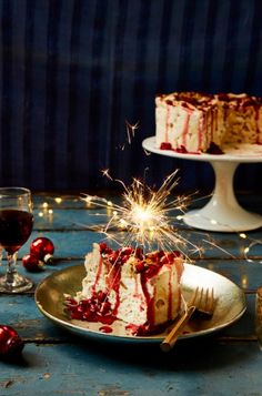 a piece of cake on a plate with a sparkler in the middle and some wine glasses next to it