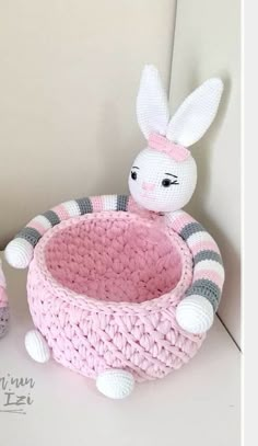 there is a crocheted basket with a stuffed rabbit in it on the floor