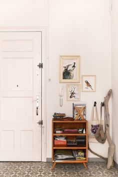 a room with a book shelf and pictures on the wall next to an open door