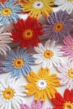 colorful crocheted flowers are arranged in rows