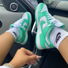 a woman's hand holding onto the door handle of a car with green and white sneakers