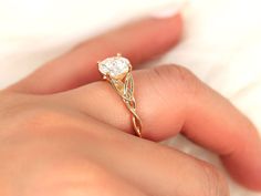 a woman's hand holding a gold ring with a diamond in it and the band on her finger