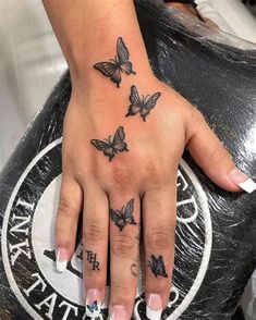 a woman's hand with three butterflies on it