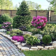 a garden filled with lots of flowers next to a wooden fence