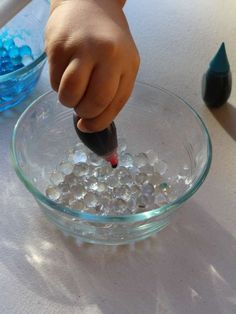 a child's hand in a glass bowl filled with water and ice cubes