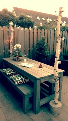 a wooden table sitting on top of a stone floor next to a bench and tree