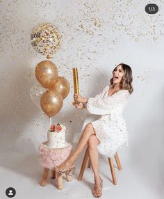 a woman sitting in front of a cake and balloons