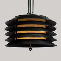 a large black light fixture hanging from a metal ceiling lamp with wood accents and round shades