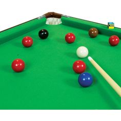 a green pool table with several balls and cues on the top, including one red ball