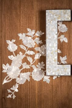 some white flowers are next to a letter on a wooden table with the letter e spelled out