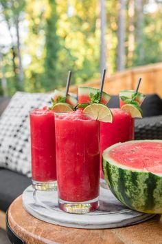 three glasses filled with watermelon juice and garnished with limes