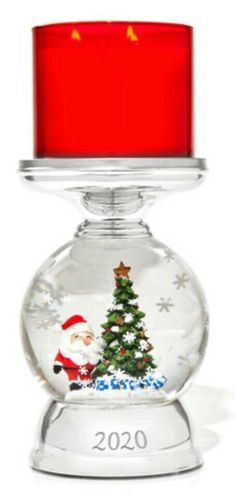 a snow globe with a christmas tree inside and a red candle in the center, on a white background