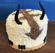 the cake is decorated with white and brown frosting, black horns on it's head