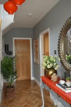 the hallway is decorated with red and white flowers, potted plants, and a large round mirror