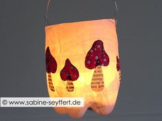 a paper lantern with red and white designs hanging from it's side on a gray background