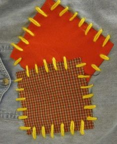 two pieces of fabric with yellow pins sticking out of them on a blue jean jacket