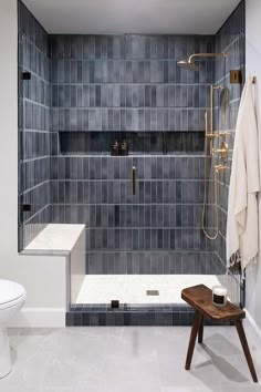 a white toilet sitting next to a walk in shower with blue tiles on the walls