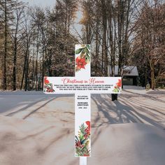 a white cross with red flowers on it in the middle of a snow covered field