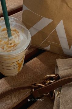 a drink sitting on top of a wooden table next to a brown bag