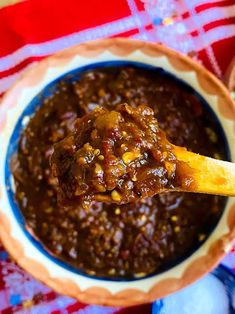 a spoon full of chili sauce on top of a red and white checkered table cloth