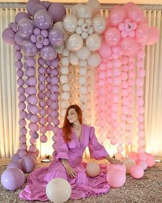 a woman sitting on the ground surrounded by balloons