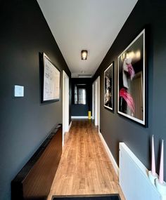 a long hallway with pictures on the wall and wood flooring in front of it