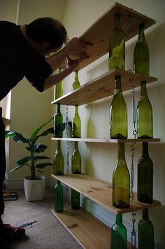 a man standing next to a shelf filled with green bottles