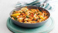 a pan filled with shrimp and rice on top of a blue plate