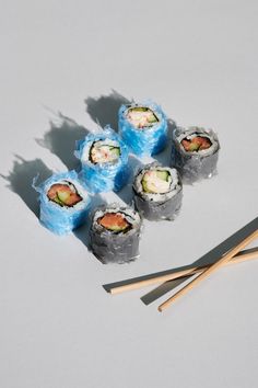 sushi rolls and chopsticks on a white surface with shadows coming from them