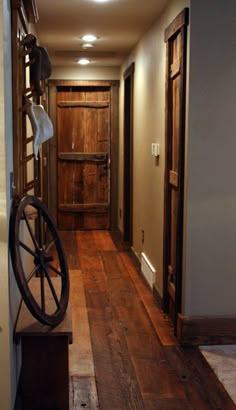 an empty hallway with a wheel on the wall and wood floors in front of it