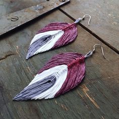 two pairs of earrings with different colored feathers on them