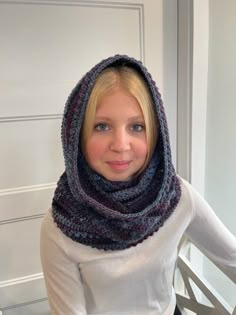 a woman with blonde hair wearing a knitted cowl around her neck and looking at the camera