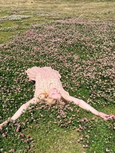 a woman laying on the ground in a field of flowers