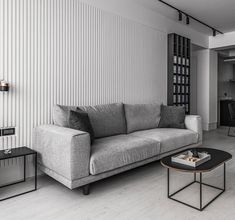 a living room with a gray couch and coffee table next to a white striped wall