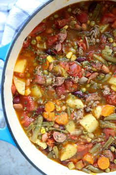 a pot filled with stew and vegetables on top of a blue cloth next to a white towel