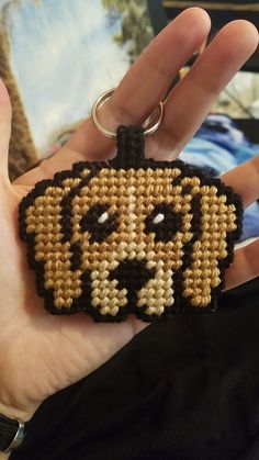 a hand holding a beaded keychain shaped like a dog's face