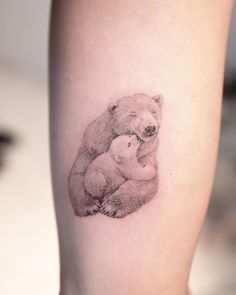 a woman's leg with a small tattoo of a bear holding a baby bear