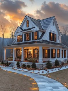 a large white house with black shutters and lights on the front porch at dusk