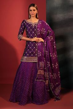 Purple kurta with gota foil embroidery in checkered pattern and leaf neckline. Paired with attached cancan skirt with bandhani woven motifs and dupatta.
Components: 3
Pattern: Embroidery, Woven
Type Of Work: Gota foil, bandhani
Neckline: Leaf neck
Sleeve Type: Three quarter
Fabric: Silk
Color: Purple
Other Details: 
Tassel embellished dupatta
Attached lining
Length:
Kurta: 36 inches
Skirt: 42 inches
Disclaimer: These are made to order designer styles, hence expect a slight variation from the ima Wedding Sharara, Designer Sharara Suits, Kurta Skirt, Plazzo Suits, Shamita Shetty, Bandhani Dress, Georgette Tops, Sharara Suit, Party Kleidung