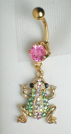 a gold colored belly ring with a pink and green frog on it