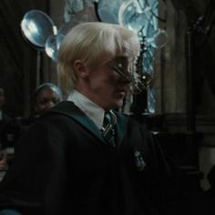 harry potter with blonde hair and glasses in hogwart's castle, looking at his watch