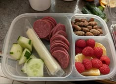 a plastic container filled with meat, fruit and veggies on top of a counter