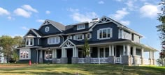 a large blue house sitting on top of a lush green field