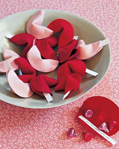 a bowl filled with red and pink felt hearts on top of a tablecloth covered table