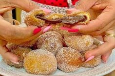 two hands holding doughnuts on a white plate