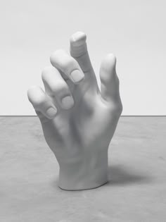 a white hand statue on top of a cement floor