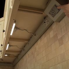 a kitchen with white cabinets and lights on the ceiling, in someone's hand