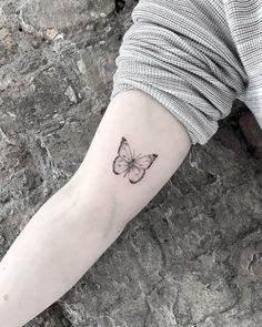 a woman's arm with a small butterfly tattoo on the left side of her arm