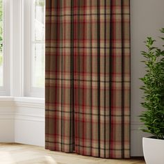 a window with a brown and red checkered curtain next to a potted plant