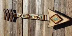 an arrow shaped wall hanging on the side of a wooden fence